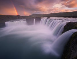A bright rainbow shines behind the wonderful Goðafoss waterfall.